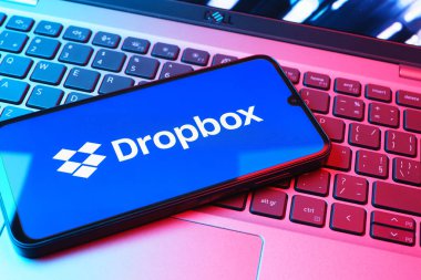 Prag, Çek Cumhuriyeti - 08 01 2025: Laptop klavyesinde duran bir cep telefonu Dropbox logosunu gösterir. Dropbox bulut depolama ve dosya paylaşımı için bir platformdur.