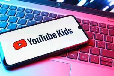 Prag, Çek Cumhuriyeti - 08 01 2025: Laptop klavyesinde duran bir cep telefonu Youtube Kids logosunu gösteriyor. Youtube Kids çocuk dostu video içeriği için bir platformdur.