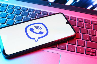 Prag, Çek Cumhuriyeti - 08 01 2025: Dizüstü bilgisayarın üzerinde duran bir cep telefonu Viber logosunu gösteriyor. Viber aramalar, mesajlar ve medya paylaşımı için bir mesajlaşma uygulamasıdır.