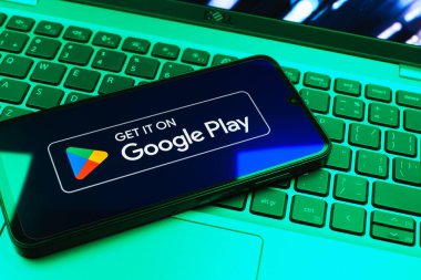 Prag, Çek Cumhuriyeti - 08 01 2025: Dizüstü bilgisayarda bulunan bir cep telefonu Google Play logosunu görüntüler. Google Play uygulamaları, oyunları ve dijital içeriği indirmek için bir platformdur.