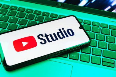 Prag, Çek Cumhuriyeti - 08 01 2025: Laptop klavyesinde duran bir cep telefonu Youtube Stüdyo logosunu görüntüler. Youtube Studio YouTube kanallarını yönetmek ve analiz etmek için bir platformdur.
