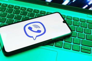 Prag, Çek Cumhuriyeti - 08 01 2025: Dizüstü bilgisayarın üzerinde duran bir cep telefonu Viber logosunu gösteriyor. Viber aramalar, mesajlar ve medya paylaşımı için bir mesajlaşma uygulamasıdır.