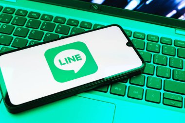 Prag, Çek Cumhuriyeti - 08 01 2025: Dizüstü bilgisayarın üzerinde duran bir cep telefonu Hat logosunu gösterir. Line aramalar, mesajlar ve çokluortam paylaşımı için bir mesajlaşma uygulamasıdır.