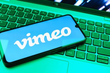 Prag, Çek Cumhuriyeti - 08 01 2025: Dizüstü bilgisayarın üzerinde duran bir cep telefonu Vimeo logosunu gösterir. Vimeo, yüksek kaliteli video sunucu ve paylaşımı için bir platformdur.