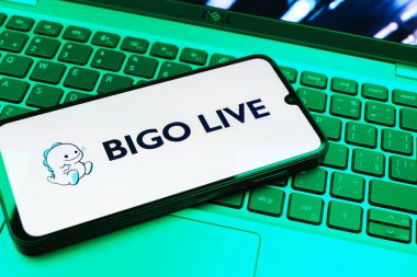 Prag, Çek Cumhuriyeti - 08 01 2025: Dizüstü bilgisayarın üzerinde duran bir cep telefonu Bigo Live logosunu gösteriyor. Bigo Live canlı yayın ve sosyal etkileşim için bir platformdur.