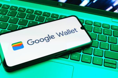 Prag, Çek Cumhuriyeti - 08 01 2025: Dizüstü bilgisayarda bulunan bir cep telefonu Google Cüzdan logosunu görüntüler. Google Cüzdanı dijital ödeme yöntemlerini depolamak ve kullanmak için bir platformdur.