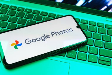Prag, Çek Cumhuriyeti - 08 01 2025: Laptop klavyesinde duran bir cep telefonu Google Photos logosunu görüntüler. Google Fotoğrafları fotoğraf ve videoları saklamak ve düzenlemek için bir platformdur.
