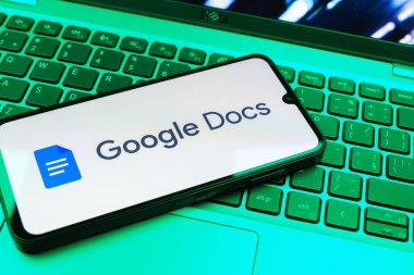 Prag, Çek Cumhuriyeti - 08 01 2025: Dizüstü bilgisayarda bulunan bir cep telefonu Google Docs logosunu görüntüler. Google Docs metin belgeleri oluşturmak ve düzenlemek için bir platformdur.