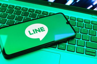 Prag, Çek Cumhuriyeti - 08 01 2025: Dizüstü bilgisayarın üzerinde duran bir cep telefonu Hat logosunu gösterir. Line aramalar, mesajlar ve çokluortam paylaşımı için bir mesajlaşma uygulamasıdır.