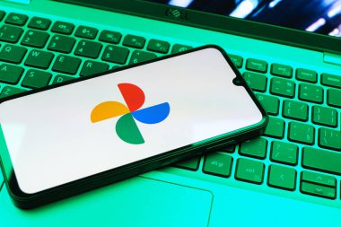 Prag, Çek Cumhuriyeti - 08 01 2025: Laptop klavyesinde duran bir cep telefonu Google Photos logosunu görüntüler. Google Fotoğrafları fotoğraf ve videoları saklamak ve düzenlemek için bir platformdur.