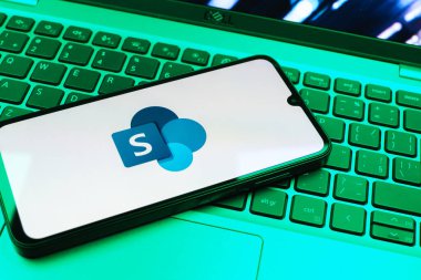 Prag, Çek Cumhuriyeti - 08 01 2025: Dizüstü bilgisayarın üzerinde duran bir cep telefonu Microsoft Sharepoint logosunu gösteriyor. Microsoft Sharepoint işbirliği ve belge yönetimi için bir platformdur.