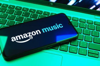 Prag, Çek Cumhuriyeti - 08 01 2025: Laptop klavyesinde uzanan bir cep telefonu Amazon Müzik logosunu gösteriyor. Amazon Müzik müzik müzik için bir platformdur..