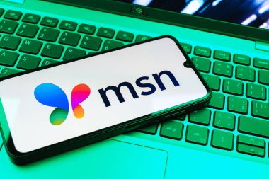 Prag, Çek Cumhuriyeti - 08 01 2025: Dizüstü bilgisayarın üzerinde duran bir cep telefonu MSN logosunu gösterir. MSN haber, e-posta ve çevrimiçi hizmetler için bir platformdur.