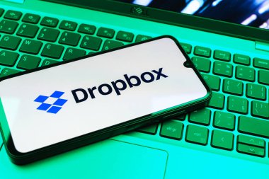Prag, Çek Cumhuriyeti - 08 01 2025: Laptop klavyesinde duran bir cep telefonu Dropbox logosunu gösterir. Dropbox bulut depolama ve dosya paylaşımı için bir platformdur.