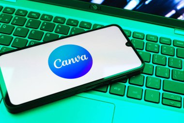 Prag, Çek Cumhuriyeti - 08 01 2025: Laptop klavyesinde duran bir cep telefonu Canva logosunu gösteriyor. Canva grafik, sunum ve tasarımlar yaratmak için bir platformdur..