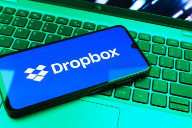 Prag, Çek Cumhuriyeti - 08 01 2025: Laptop klavyesinde duran bir cep telefonu Dropbox logosunu gösterir. Dropbox bulut depolama ve dosya paylaşımı için bir platformdur.