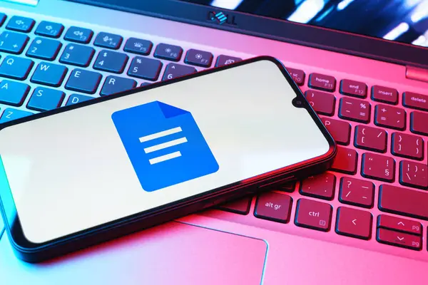 Prag, Çek Cumhuriyeti - 08 01 2025: Dizüstü bilgisayarda bulunan bir cep telefonu Google Docs logosunu görüntüler. Google Docs metin belgeleri oluşturmak ve düzenlemek için bir platformdur.