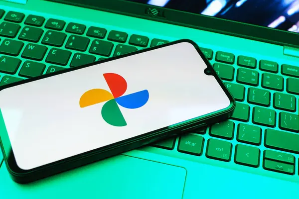 Prag, Çek Cumhuriyeti - 08 01 2025: Laptop klavyesinde duran bir cep telefonu Google Photos logosunu görüntüler. Google Fotoğrafları fotoğraf ve videoları saklamak ve düzenlemek için bir platformdur.