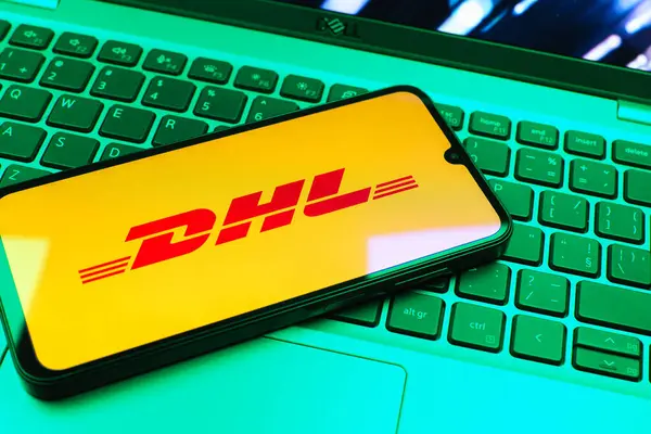 Prag, Çek Cumhuriyeti - 08 01 2025: Dizüstü bilgisayarın üzerinde duran bir cep telefonu DHL logosunu gösterir. DHL uluslararası nakliye hizmeti sunan bir lojistik şirketidir..