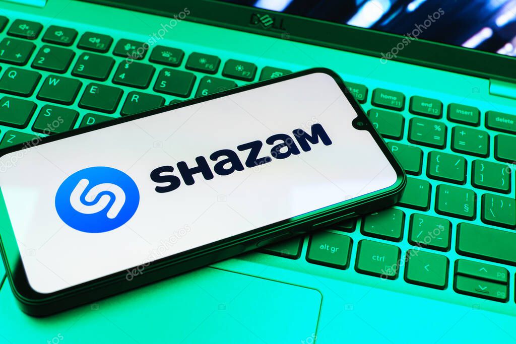 Prague, Czechia - 08 01 2025: A mobile phone lying on a laptop keyboard displays the Shazam logo. Shazam is an app for identifying songs and music tracks.