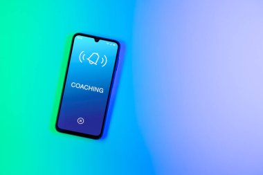 Arka plandaki telefon koçluk metnini görüntüler. Koçluk, çalışanlara beceri ve performans geliştirme konusunda rehberlik ediyor..