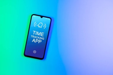 Arka plandaki telefon Zaman İzleme Uygulaması metnini görüntüler. Zaman İzleme Uygulaması günlük kaydı çalışma saatleri için bir yazılımdır.