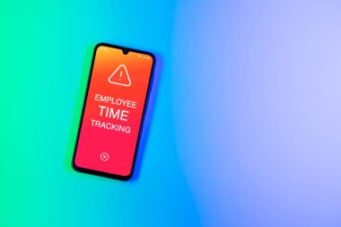 Arka plandaki telefon, Çalışan Zaman İzleme metnini görüntüler. Çalışan Zaman İzleme, çalışanların çalışma saatlerini kaydediyor..