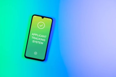 Arkaplandaki telefon Uygulamalı İzleme Sistemi metnini görüntüler. Başvuru İzleme Sistemi işe alım süreçlerini yönetmek için bir yazılımdır.