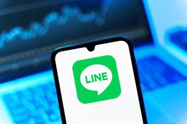 Prag, Çek Cumhuriyeti - 08 12 2025: Dizüstü bilgisayarın önünde duran bir cep telefonu Line logosunu gösteriyor. Line aramalar, mesajlar ve çokluortam paylaşımı için bir mesajlaşma uygulamasıdır.