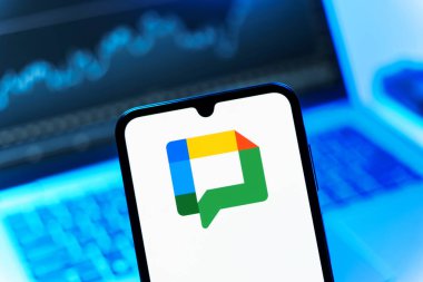 Prag, Çek Cumhuriyeti - 08 12 2025: Bir dizüstü bilgisayarın önünde duran bir cep telefonu Google Chat logosunu gösteriyor. Google Chat mesajlaşma ve takım işbirliği için bir platformdur.