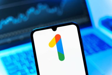 Prag, Çek Cumhuriyeti - 08 12 2025: Bir dizüstü bilgisayarın önünde duran bir cep telefonu Google One logosunu gösteriyor. Google 1 bulut depolama ve abonelik hizmetleri için bir platformdur.