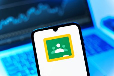 Prag, Çek Cumhuriyeti - 08 12 2025: Bir dizüstü bilgisayarın önünde duran bir cep telefonu Google Sınıfı logosunu gösteriyor. Google Sınıfı, sınıfları ve eğitim içeriğini yönetmek için bir platformdur.