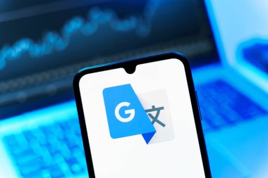Prag, Çek Cumhuriyeti - 08 12 2025: Bir dizüstü bilgisayarın önünde duran bir cep telefonu Google Translate logosunu gösterir. Google Çevirisi metni ve konuşmayı diller arası çevirmek için bir platformdur..