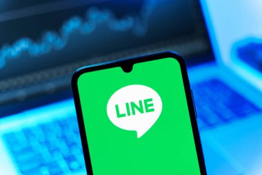 Prag, Çek Cumhuriyeti - 08 12 2025: Dizüstü bilgisayarın önünde duran bir cep telefonu Line logosunu gösteriyor. Line aramalar, mesajlar ve çokluortam paylaşımı için bir mesajlaşma uygulamasıdır.