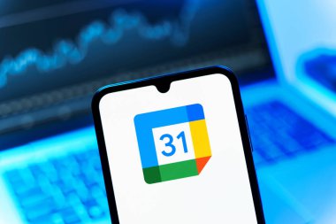 Prag, Çek Cumhuriyeti - 08 12 2025: Bir dizüstü bilgisayarın önünde duran bir cep telefonu Google takvim logosunu görüntüler. Google Takvimi olayları zamanlamak ve yönetmek için bir platformdur.