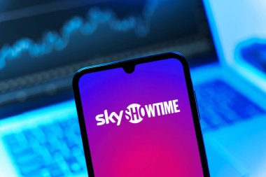 Prag, Çek Cumhuriyeti - 08 12 2025: Dizüstü bilgisayarın önünde duran bir cep telefonu SkyShowtime logosunu gösteriyor. SkyShowtime, sinema ve televizyon dizileri için bir yayın platformudur..