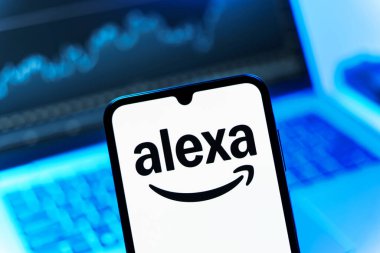 Prag, Çek Cumhuriyeti - 08 12 2025: Bir dizüstü bilgisayarın önünde duran bir cep telefonu Alexa logosunu gösteriyor. Alexa akıllı aygıtlar ve servisler için ses asistanıdır.
