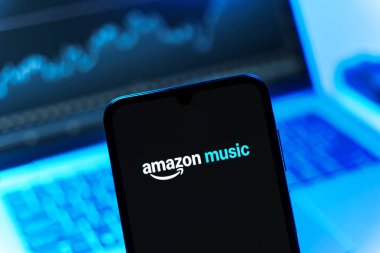 Prag, Çek Cumhuriyeti - 08 12 2025: Dizüstü bilgisayarın önünde duran bir cep telefonu Amazon Müzik logosunu gösteriyor. Amazon Müzik müzik müzik için bir platformdur..