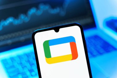 Prag, Çek Cumhuriyeti - 08 12 2025: Bir dizüstü bilgisayarın önünde duran bir cep telefonu Google TV logosunu gösteriyor. Google TV film, program ve uygulamalar için bir platformdur..