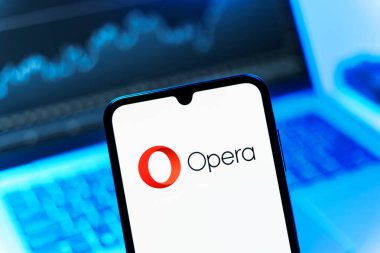 Prag, Çek Cumhuriyeti - 08 12 2025: Dizüstü bilgisayarın önünde duran bir cep telefonu Opera logosunu gösteriyor. Opera hızlı ve güvenli internet taraması için bir web tarayıcısıdır.