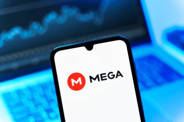 Prag, Çek Cumhuriyeti - 08 12 2025: Dizüstü bilgisayarın önünde duran bir cep telefonu Mega logosunu gösteriyor. Mega şifreli dosya paylaşımı ile bulut depolama platformu.