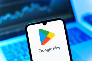 Prag, Çek Cumhuriyeti - 08 12 2025: Bir dizüstü bilgisayarın önünde duran bir cep telefonu Google Play logosunu gösteriyor. Google Play uygulamaları, oyunları ve dijital içeriği indirmek için bir platformdur.