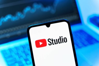 Prag, Çek Cumhuriyeti - 08 12 2025: Bir dizüstü bilgisayarın önünde duran bir cep telefonu Youtube Stüdyo logosunu gösteriyor. Youtube Studio YouTube kanallarını yönetmek ve analiz etmek için bir platformdur.