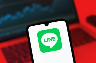 Prag, Çek Cumhuriyeti - 08 12 2025: Dizüstü bilgisayarın önünde duran bir cep telefonu Line logosunu gösteriyor. Line aramalar, mesajlar ve çokluortam paylaşımı için bir mesajlaşma uygulamasıdır.