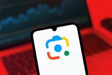 Prag, Çek Cumhuriyeti - 08 12 2025: Bir dizüstü bilgisayarın önünde duran bir cep telefonu Google Lens logosunu gösteriyor. Google Lens, resimlerdeki görsel arama ve bilgi için kullanılan bir araçtır..