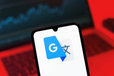 Prag, Çek Cumhuriyeti - 08 12 2025: Bir dizüstü bilgisayarın önünde duran bir cep telefonu Google Translate logosunu gösterir. Google Çevirisi metni ve konuşmayı diller arası çevirmek için bir platformdur..