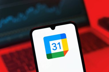 Prag, Çek Cumhuriyeti - 08 12 2025: Bir dizüstü bilgisayarın önünde duran bir cep telefonu Google takvim logosunu görüntüler. Google Takvimi olayları zamanlamak ve yönetmek için bir platformdur.