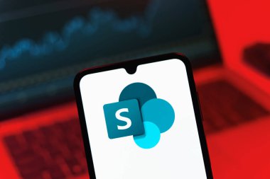 Prag, Çek Cumhuriyeti - 08 12 2025: Bilgisayarın önünde duran bir cep telefonu Microsoft Sharepoint logosunu gösteriyor. Microsoft Sharepoint işbirliği ve belge yönetimi için bir platformdur.