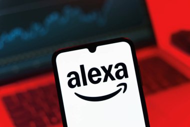 Prag, Çek Cumhuriyeti - 08 12 2025: Bir dizüstü bilgisayarın önünde duran bir cep telefonu Alexa logosunu gösteriyor. Alexa akıllı aygıtlar ve servisler için ses asistanıdır.