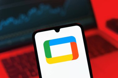 Prag, Çek Cumhuriyeti - 08 12 2025: Bir dizüstü bilgisayarın önünde duran bir cep telefonu Google TV logosunu gösteriyor. Google TV film, program ve uygulamalar için bir platformdur..